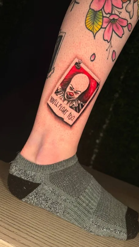 Tattoo of framed black and grey portrait against a red background above an ankle