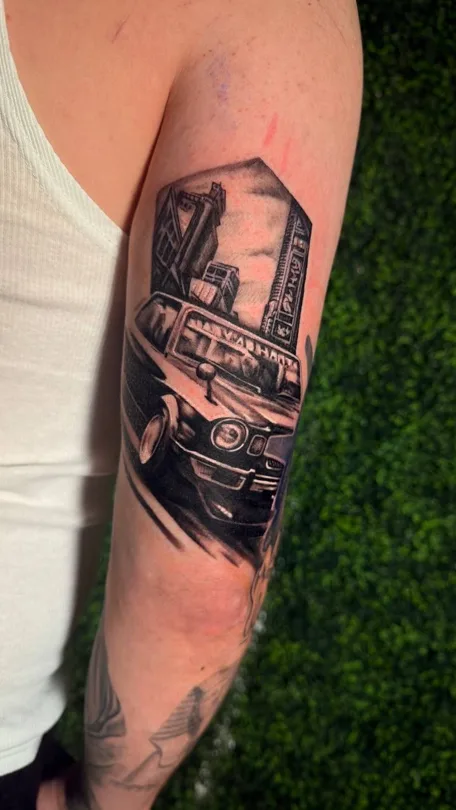 Black and grey framed scene with detailed mechanical forms tattoo on an arm