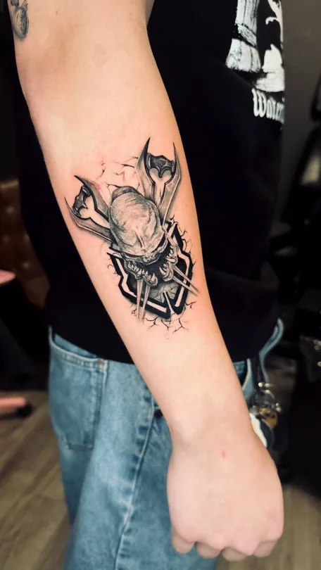 Angular black and grey helmet tattoo on a forearm