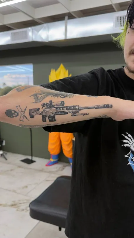 Black and grey mechanical object tattoo along a forearm