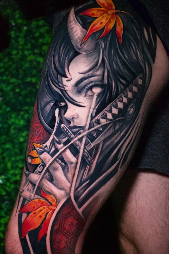 Illustrated face with a sword, red accents and orange maple leaves tattoo on an upper arm