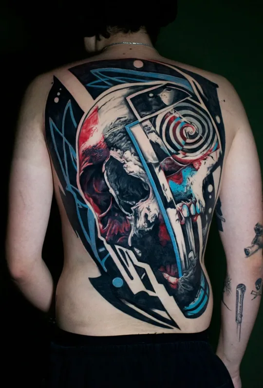 Color skull and mechanical composition tattoo across a back